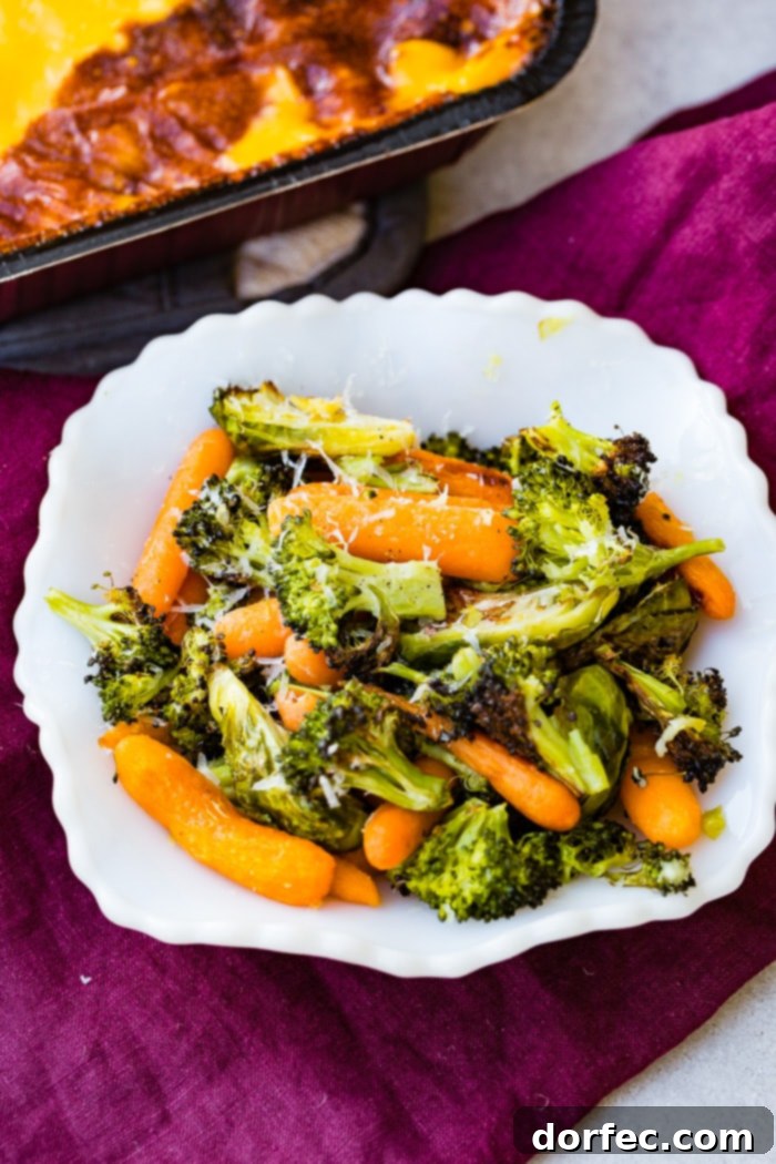 A white bowl filled with simple roasted garlic vegetables including carrots, brussels sprouts, and broccoli, topped with parmesan cheese