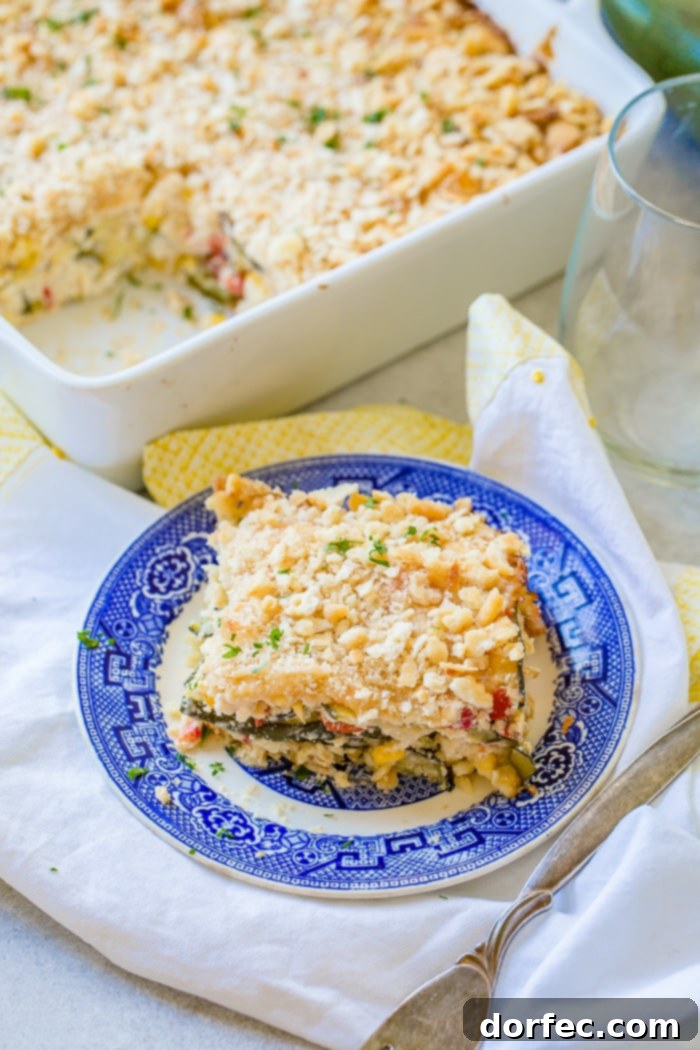 Golden Zucchini Corn Bake 4 A serving of cheesy zucchini corn casserole on a blue plate, highlighting layers of grilled zucchini, sweet corn, diced peppers, and a golden-brown cracker crust.