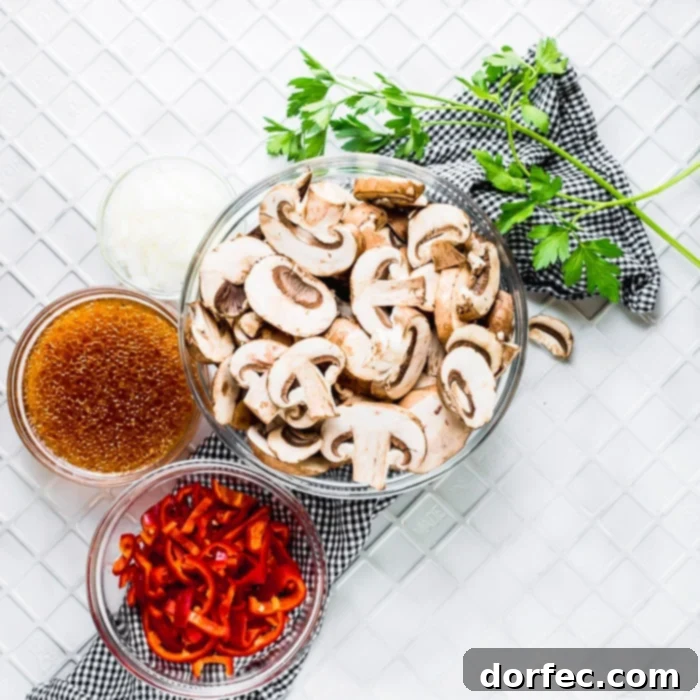 A flat lay of fresh ingredients laid out on a wooden board, including baby bella mushrooms, a red bell pepper, a yellow onion, a bottle of Italian dressing, and a bunch of parsley, ready to be prepped for the Italian Sauteed Mushrooms recipe.