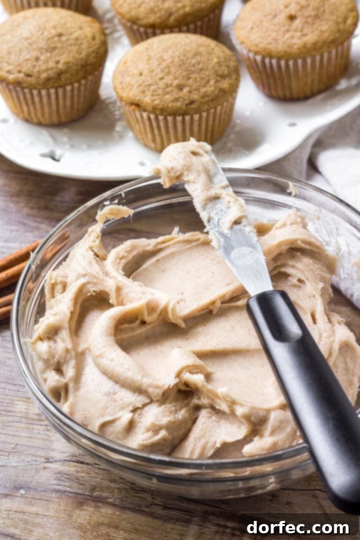 A rustic bowl filled with fluffy, cinnamon-infused cream cheese frosting, ready to adorn the spice cake cupcakes.