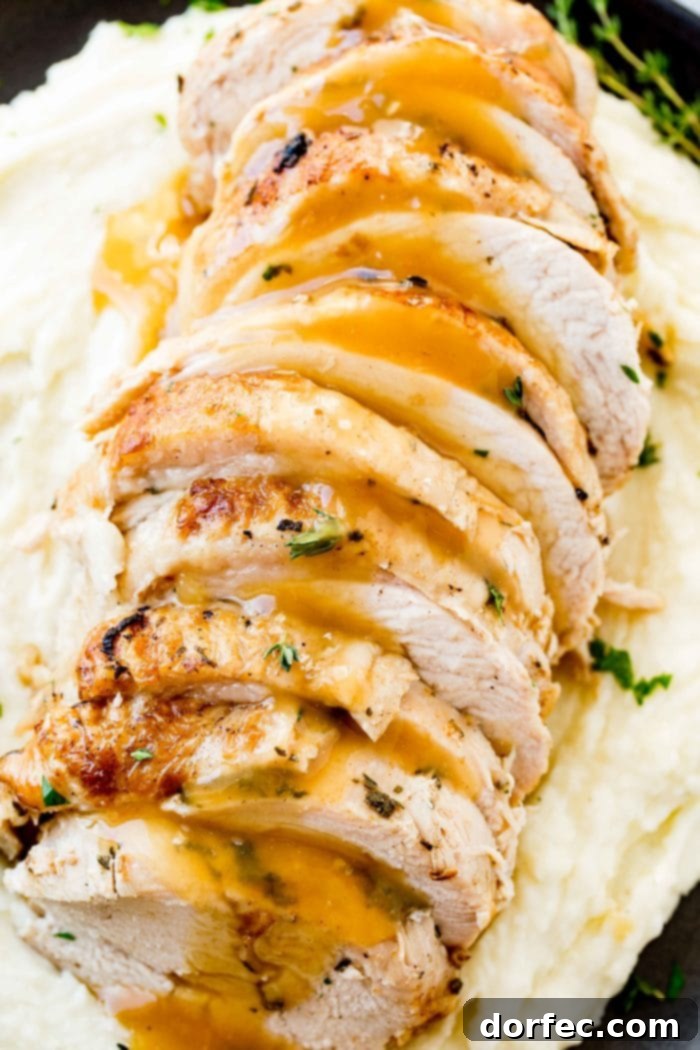 A beautifully presented plate of sliced turkey breast, generously drizzled with gravy and adorned with fresh herbs, served alongside creamy mashed potatoes.