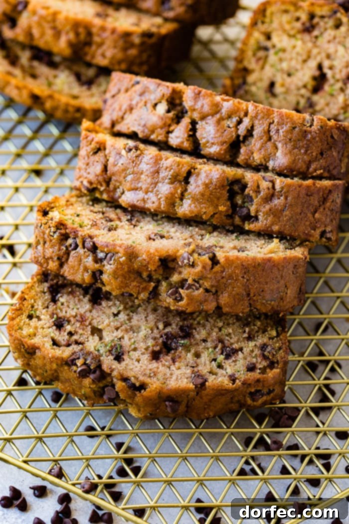 Decadent Chocolate Chip Zucchini Loaf 5 a photo of slices of chocolate chip zucchini bread tipped over on top of each other on top of a gold wire cooling rack