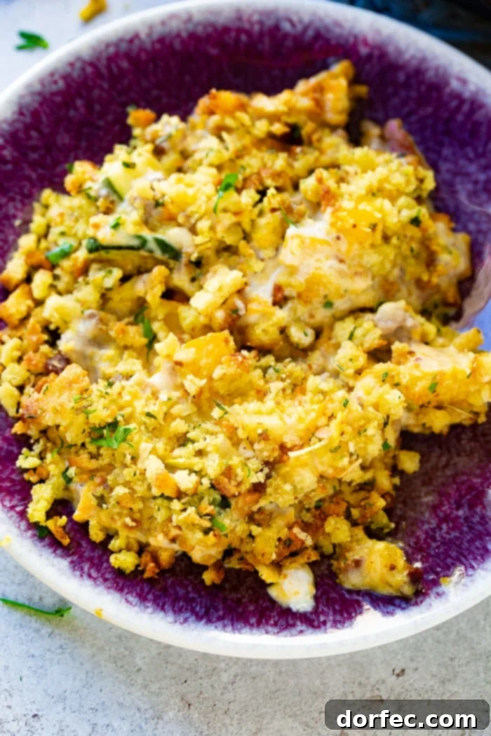 A serving of creamy zucchini sausage casserole, topped with golden stuffing, presented in a charming purple bowl.