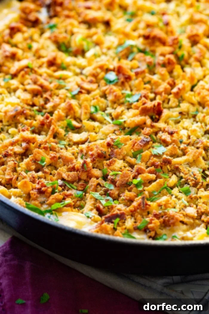 A close-up photo of a rich, creamy casserole in a cast iron skillet, blanketed with a beautifully golden and toasted stuffing topping, ready to be served.