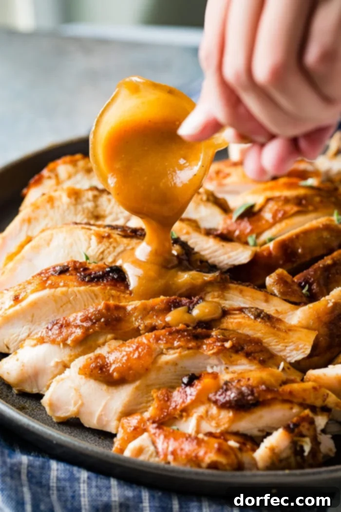A perfectly sliced apple pecan smoked turkey breast with rich gravy being poured over it, ready to serve.