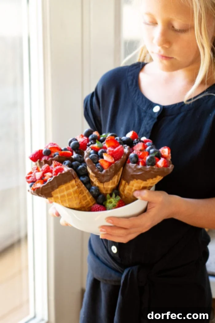 My daughter holding a bowl of waffle cones filled with berries.