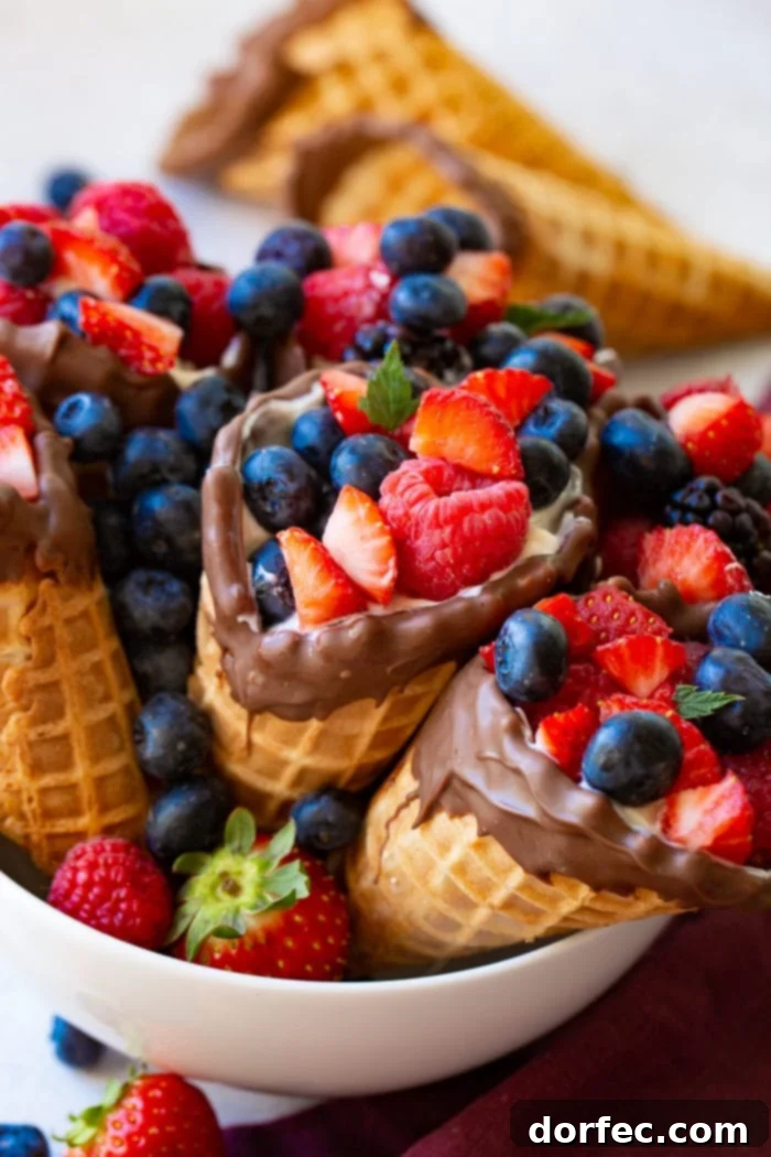 A bowl filled with fresh berries and waffle cones filled with yogurt and berries.