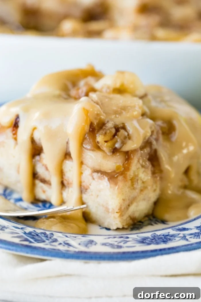 Irresistible Apple Pie Bread Pudding with Silky Vanilla Sauce 3 A large, inviting slice of apple bread pudding generously drizzled with warm vanilla sauce, presented on an elegant blue china plate.