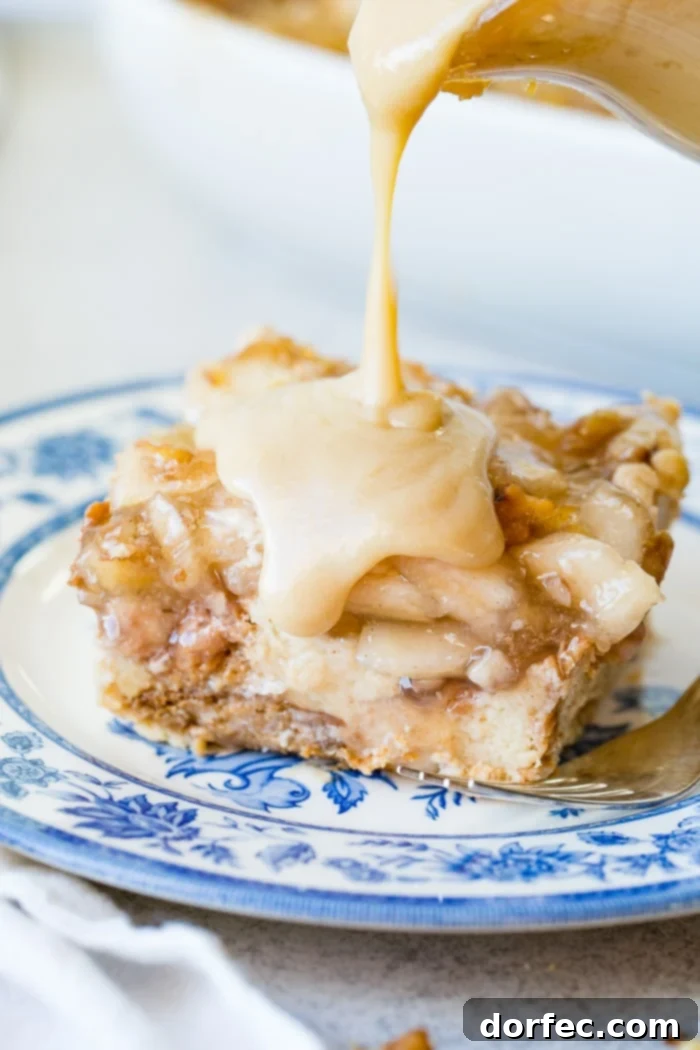 Irresistible Apple Pie Bread Pudding with Silky Vanilla Sauce 5 A tempting slice of apple pie bread pudding with a spoonful removed, revealing the soft, spiced bread and apple filling, all coated in vanilla sauce.