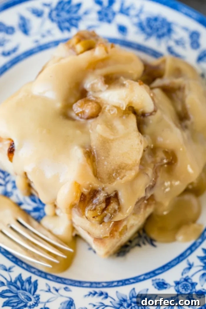 Irresistible Apple Pie Bread Pudding with Silky Vanilla Sauce 6 A close-up of a delectable slice of apple pie bread pudding, with a spoon digging in, highlighting the rich texture and vanilla sauce.