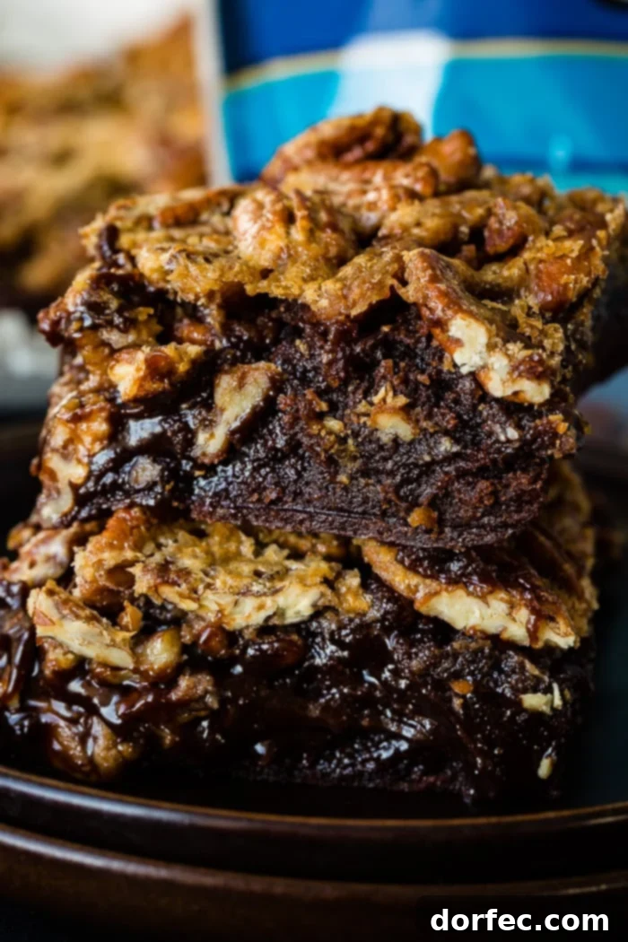 Two pecan pie brownies stacked together, showcasing the gooey pecan topping.