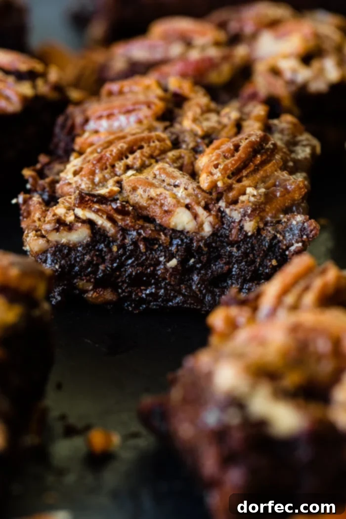Close-up of two pecan pie brownies, highlighting the glossy pecan topping.