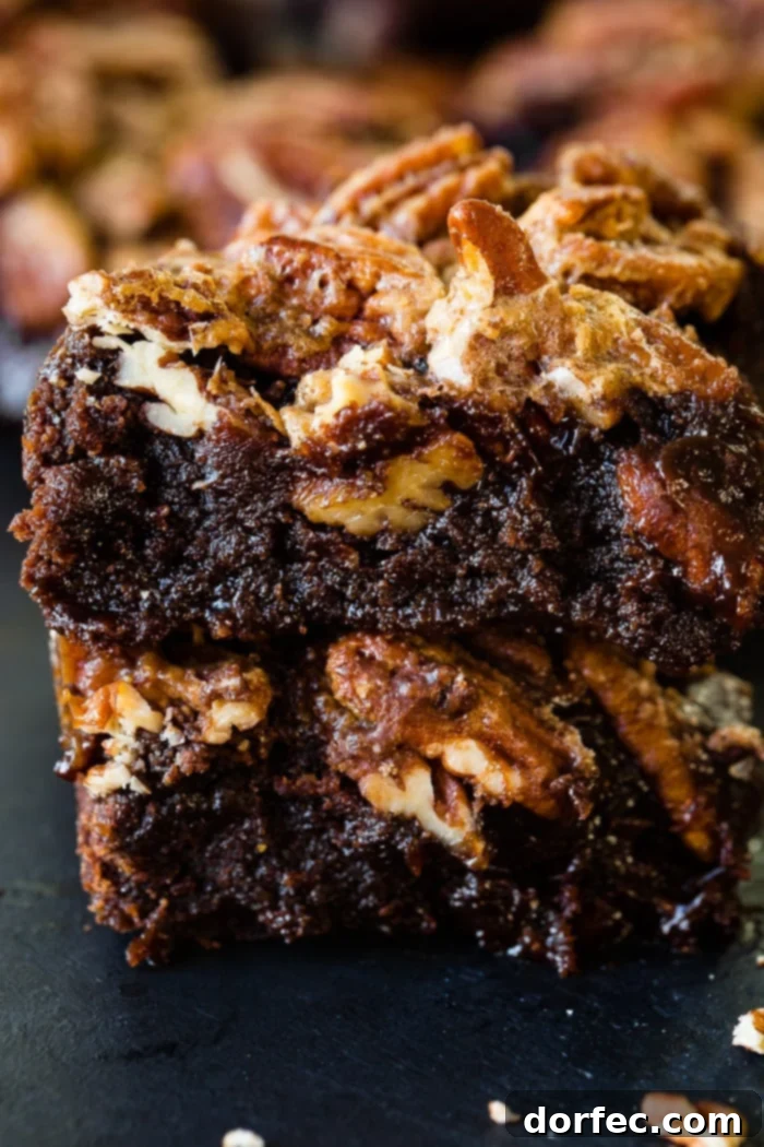 Four pecan pie brownies stacked, showing a generous pecan topping.