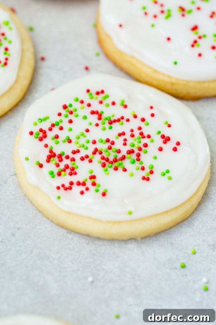 A perfectly frosted white chocolate sugar cookie with peppermint royal icing, topped with vibrant red and green sprinkles, ready for the holidays.