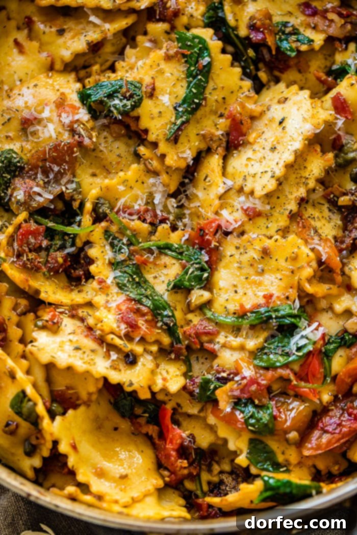 Close-up of a skillet brimming with golden-crisp pancetta mixed with tender ravioli, bright sun-dried tomatoes, and wilted spinach.