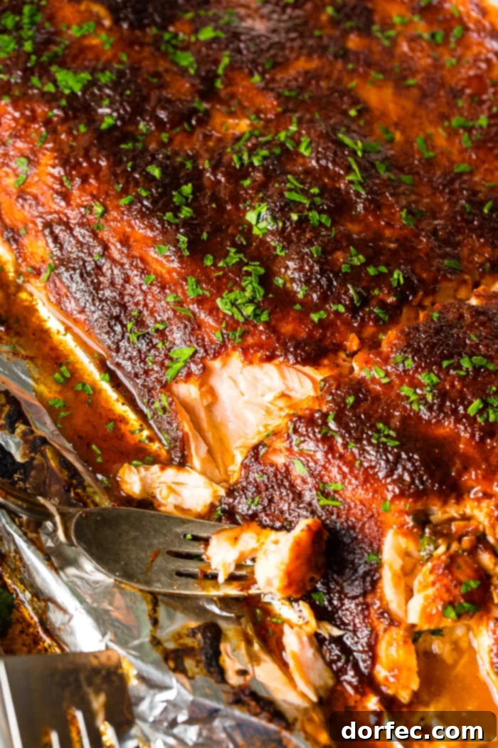 Fork taking a bite of healthy maple glazed salmon baked in foil