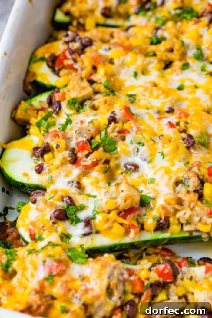 A beautifully arranged casserole dish of Cheesy Healthy Mexican Zucchini Boats, generously filled with a colorful mix of brown rice, black beans, corn, peppers, and tomatoes, all topped with melted Colby Jack cheese and fresh cilantro.