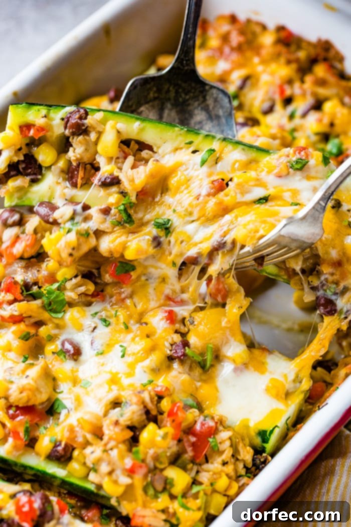 Close-up of the Cheesy Healthy Mexican Zucchini Boats in the casserole dish, showcasing the bubbling, perfectly melted cheese on top of the vibrant filling.