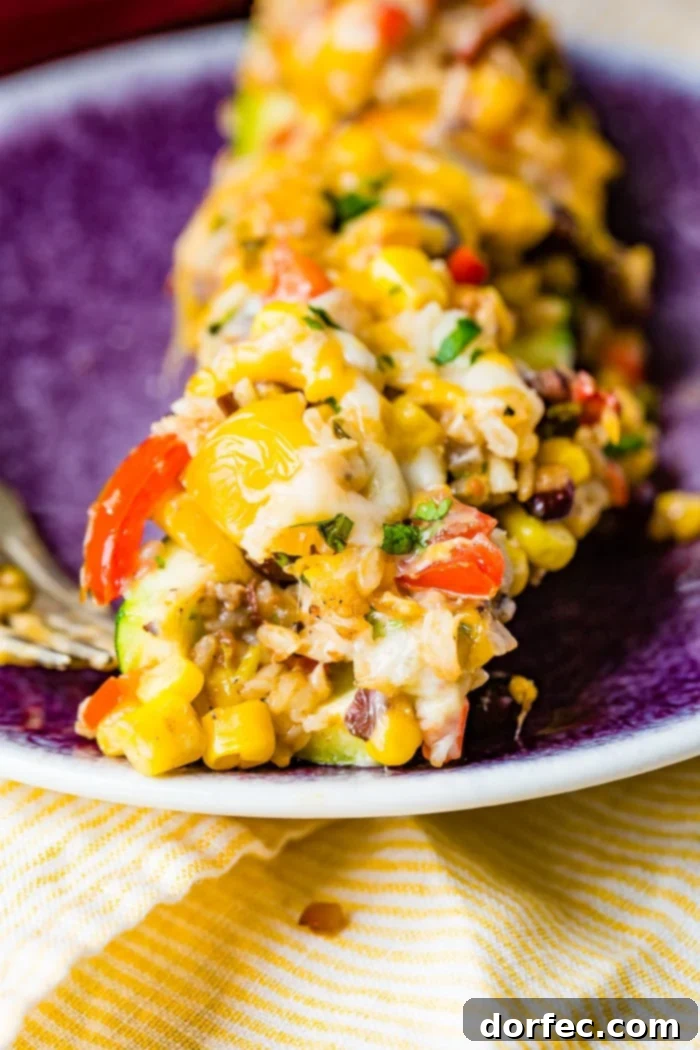 A vibrant close-up shot of a single Cheesy Healthy Mexican Zucchini Boat, ready to be eaten, showcasing its cheesy topping, colorful filling, and tender zucchini base.