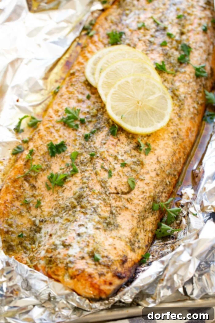 A perfectly baked salmon fillet glistening with garlic butter, garnished with fresh parsley and lemon slices, ready to be served