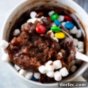 A delicious hot cocoa mug brownie for one, topped with whipped cream and chocolate sprinkles, ready to be enjoyed.