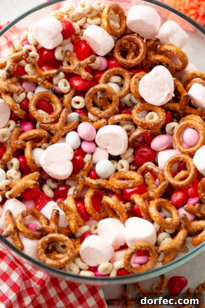 A close-up view of the Valentine's Snack Mix, highlighting the delicious blend of frosted Cheerios, Valentine's caramel M&M's, X and O pretzels, pink heart marshmallows, and Starburst jelly beans.