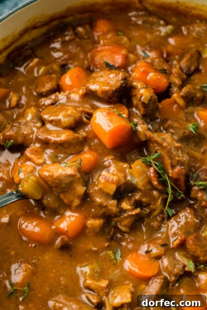 A hearty bowl of Irish Beef Stew, rich with tender beef, vibrant carrots, and celery in a savory, thick gravy, served hot.