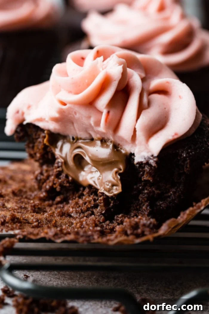 Choco-Berry Nutella Bliss Cupcakes 2 A close-up of a rich chocolate cupcake, cut open to reveal a gooey Nutella center, topped with a swirl of fluffy pink strawberry buttercream frosting and a delicate fresh strawberry slice.