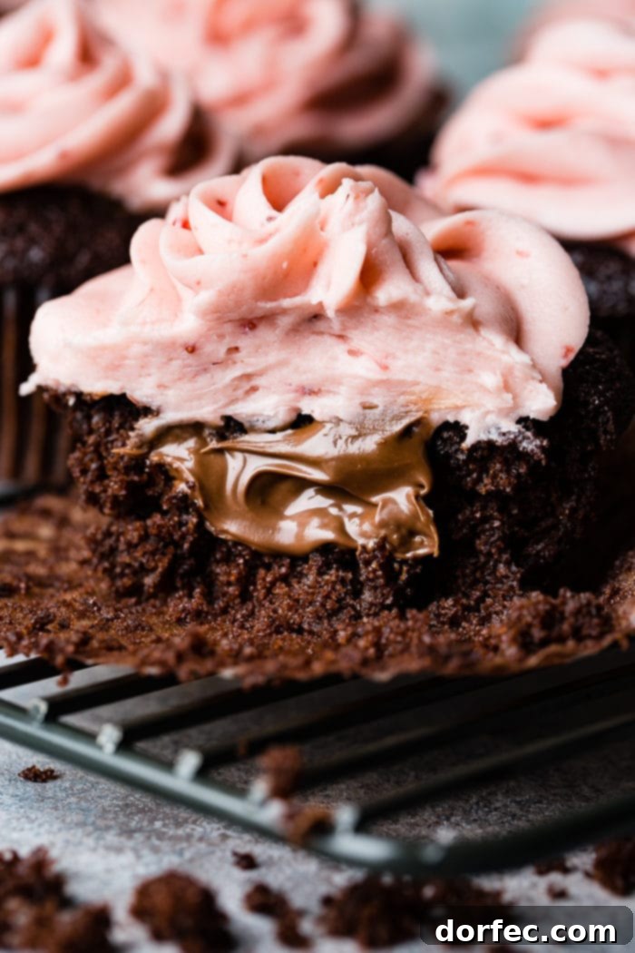 Choco-Berry Nutella Bliss Cupcakes 4 A vibrant close-up of a Nutella-filled chocolate cupcake, expertly frosted with pastel pink strawberry buttercream, garnished with a single fresh strawberry.