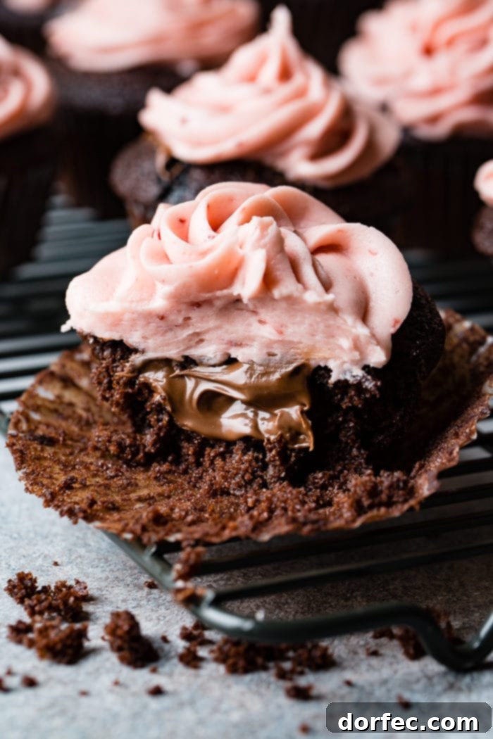 Choco-Berry Nutella Bliss Cupcakes 6 A stunning shot of a Nutella-filled chocolate cupcake, exquisitely frosted with strawberry buttercream and a fresh strawberry, ready to be devoured.