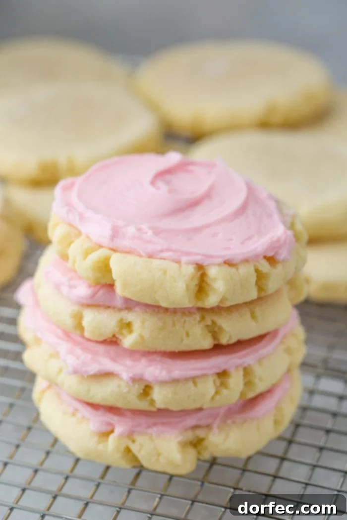 Copycat Swig Sugar Cookies and Signature Frosting 4 A stack of four perfectly frosted Swig Sugar Cookies, with unfrosted cookies blurred in the background, emphasizing the alluring pink frosting.