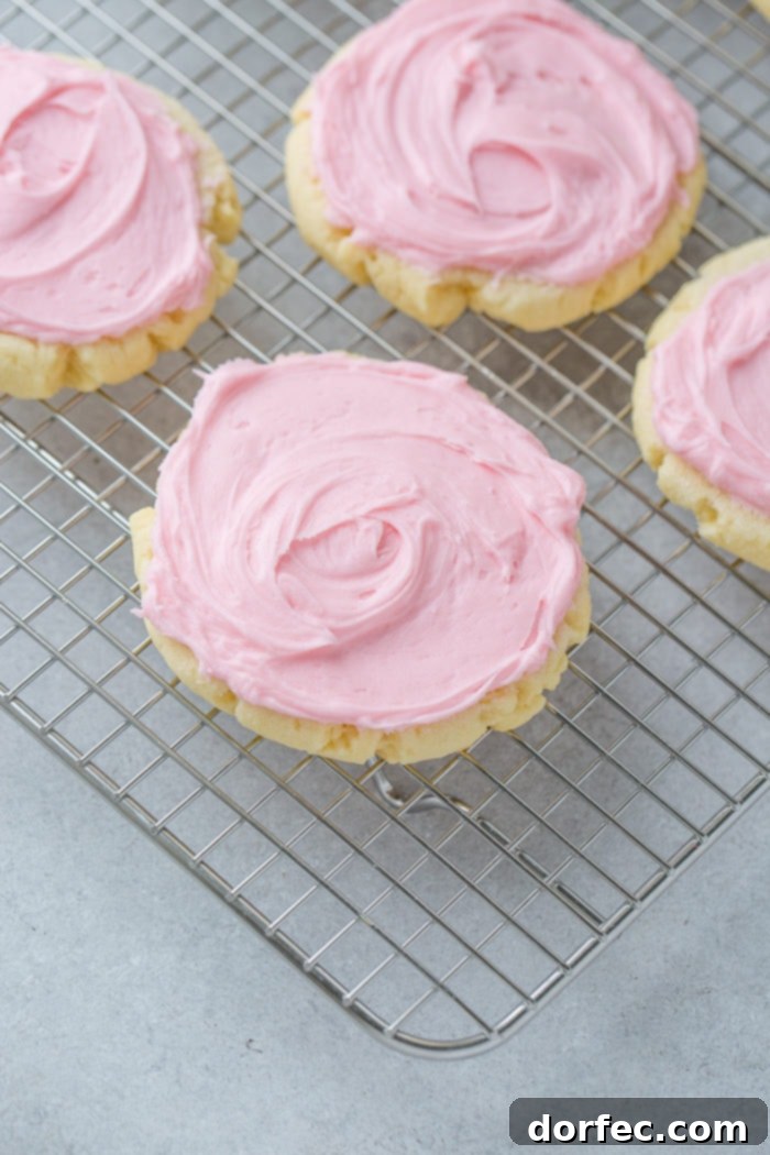Copycat Swig Sugar Cookies and Signature Frosting 6 A collection of Swig Sugar Cookies with signature pink frosting, centered around one cookie, beautifully arranged on a cooling rack, tempting to eat.