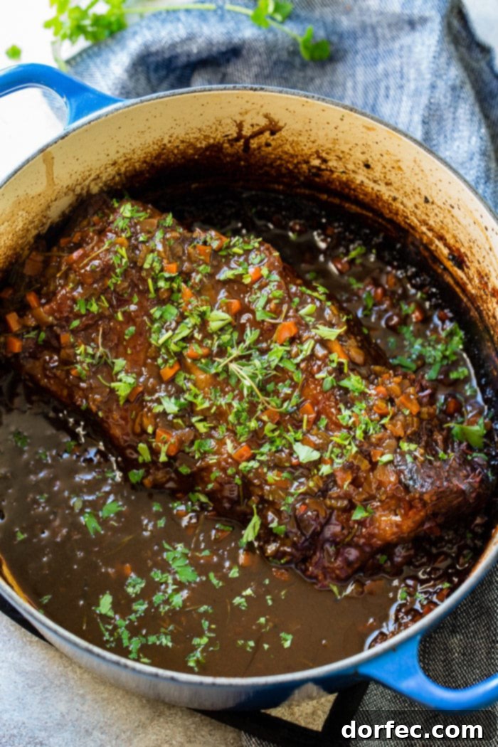 Fork-Tender Beef Roast 5 A photo of a braised chuck roast sitting in all its beautiful juices in a dutch oven pot.