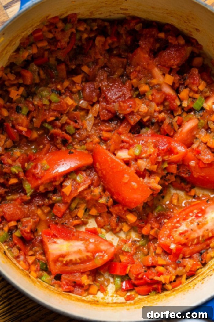 A photo of the base for chicken tortilla soup including sauteed onions, carrots, bell peppers, and celery as well as roma tomatoes.