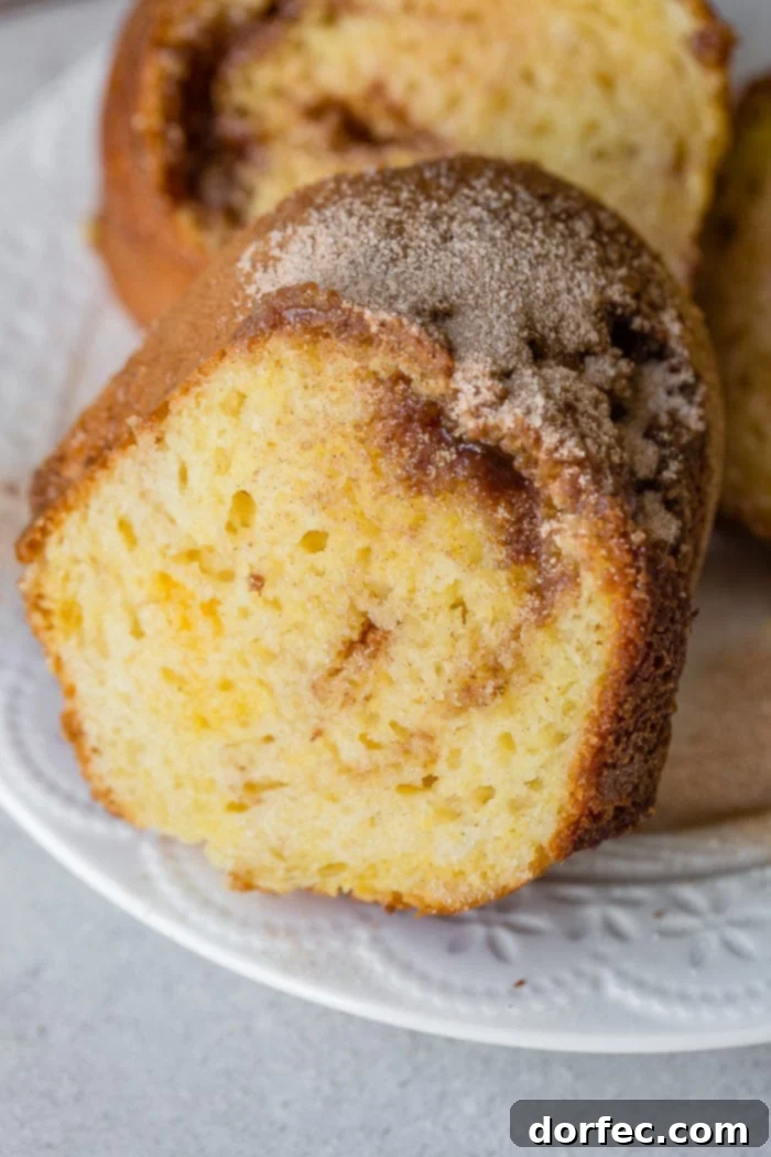 A beautifully sliced brown sugar cinnamon bundt cake, revealing cinnamon sugar swirls within and a crackly sugary crust.