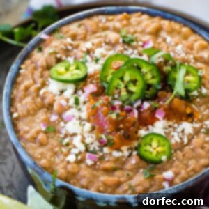 a bowl of instant pot refried beans with cheese, salsa, and jalapenos on top