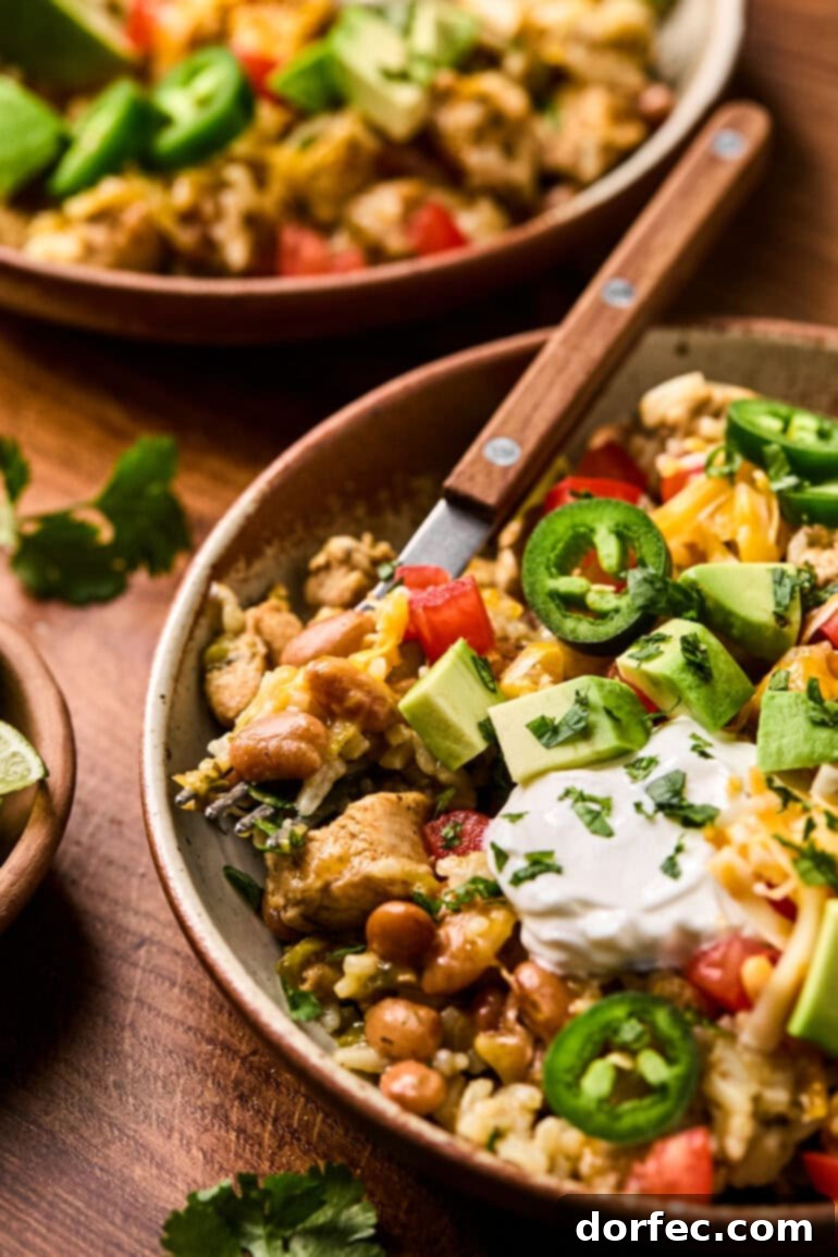 Flavor-Packed Instant Pot Cilantro Lime Chicken Burrito Bowls 12 A beautifully presented chicken burrito bowl in a rustic wooden bowl, generously topped with sliced jalapeños, a swirl of sour cream, and creamy avocado chunks.
