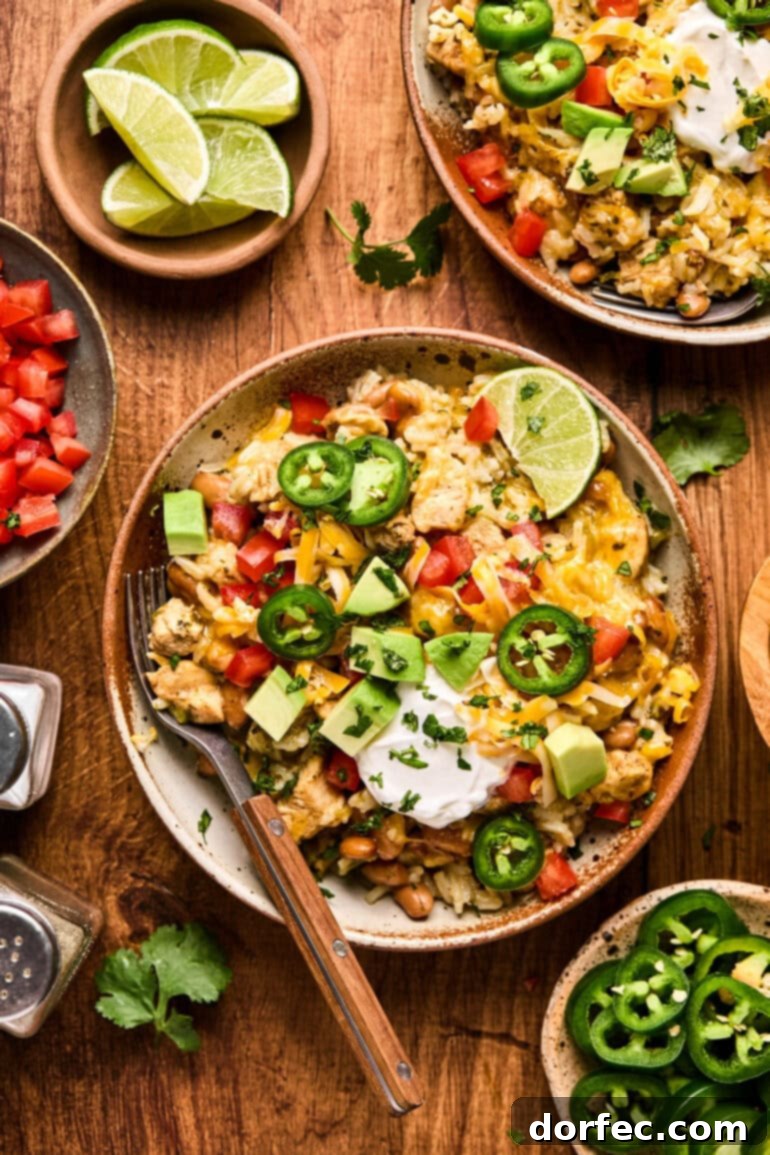 Flavor-Packed Instant Pot Cilantro Lime Chicken Burrito Bowls 13 A chicken burrito bowl generously topped with sliced jalapeños, a dollop of sour cream, vibrant diced tomatoes, and creamy chunks of avocado, showcasing fresh ingredients.