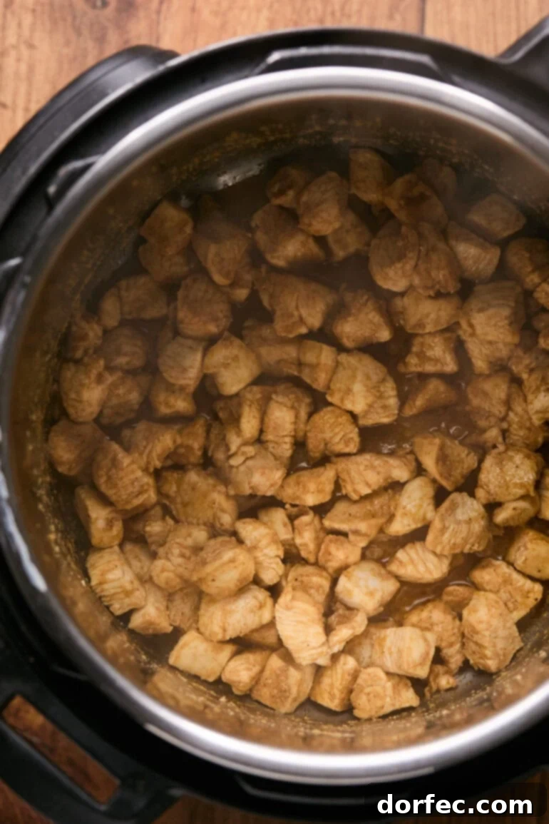 Flavor-Packed Instant Pot Cilantro Lime Chicken Burrito Bowls 5 Chopped seasoned chicken breasts sizzling in the Instant Pot on sauté mode, developing a golden sear.