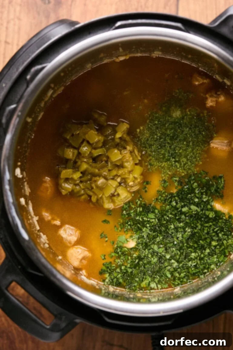 Flavor-Packed Instant Pot Cilantro Lime Chicken Burrito Bowls 7 Chicken broth and green chiles added to the Instant Pot, with ingredients ready for stirring.