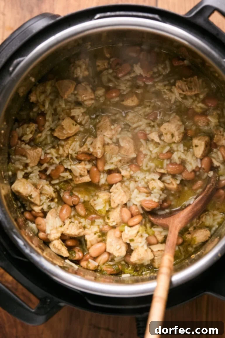 Flavor-Packed Instant Pot Cilantro Lime Chicken Burrito Bowls 10 Cooked cilantro lime chicken and rice being gently stirred in the Instant Pot after pressure release, ready for cheese.