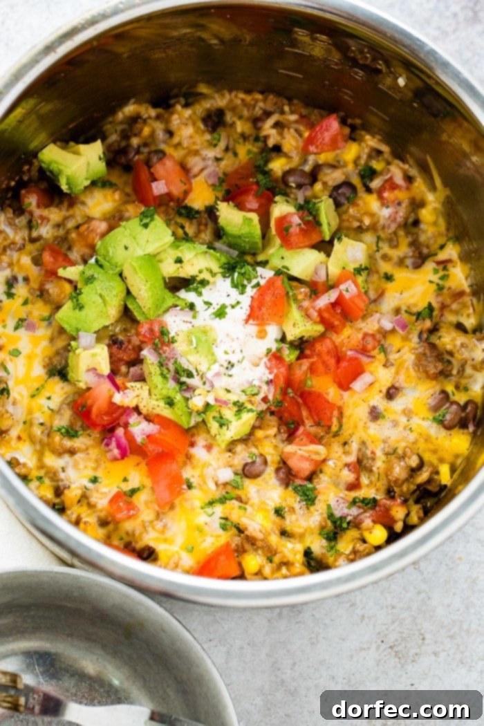 A beautifully presented Instant Pot ground beef burrito bowl, garnished with vibrant chopped tomatoes, creamy avocado, and fresh cilantro, promising a healthy and delicious family meal.