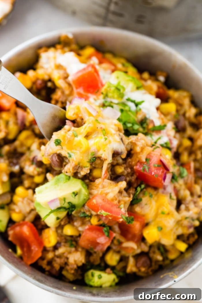A delightful Instant Pot ground beef burrito bowl being sampled with a fork, showcasing its rich textures and appealing colors, ready for a quick, family-friendly dinner.