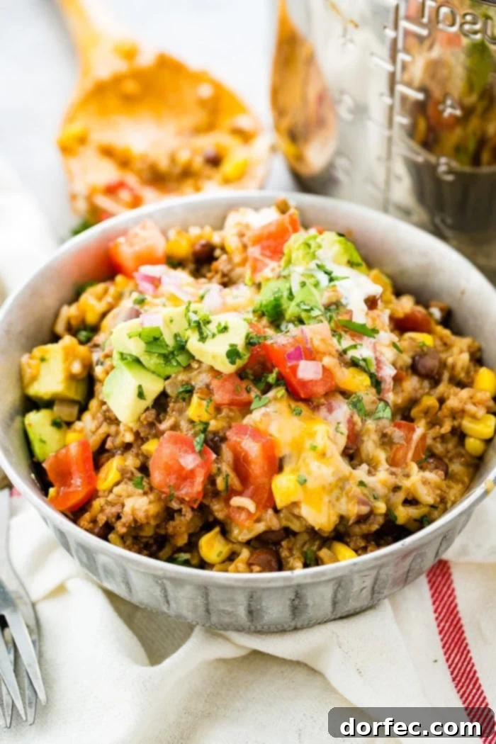 A close-up of a delectable Instant Pot ground beef burrito bowl, richly topped with fresh tomatoes, creamy avocado, and vibrant cilantro, highlighting its appealing textures.