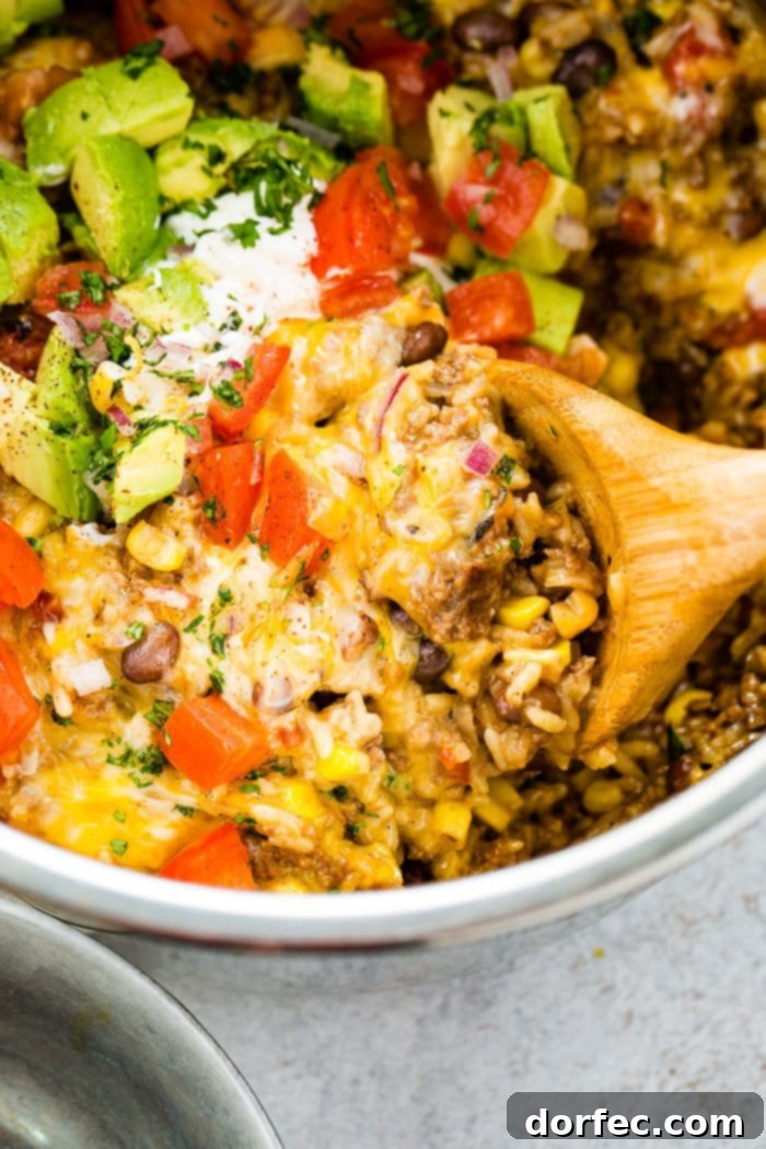 A hearty scoop being taken from a freshly prepared Instant Pot ground beef burrito bowl, brimming with savory ingredients and fresh garnishes, perfect for a fulfilling meal.