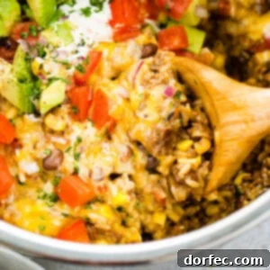 an instant pot full of ground beef and rice burrito bowls with a wooden spoon taking out a scoop