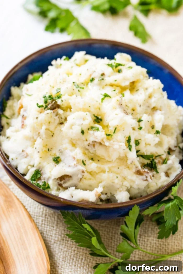 Crispy Smashed Steakhouse Potatoes 3 A close-up shot of a blue serving bowl brimming with chunky smashed potatoes, beautifully garnished with fresh chopped parsley.
