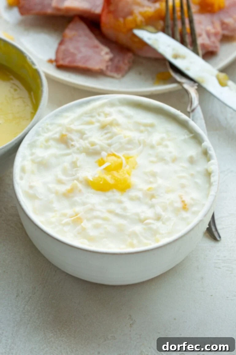 a photo of a pina colada ham dipping sauce in a small bowl with ham slices in the background