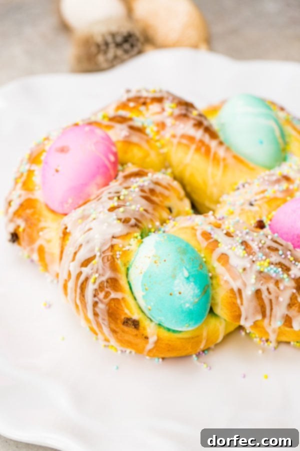Italian Easter Bread Recipe with Video 2 A photo of Italian Easter bread with bright hard boiled eggs nestled in it, and covered in sprinkles and a sweet glaze.