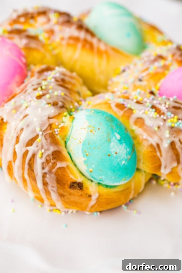Italian Easter Bread Recipe with Video 3 A photo of Italian Easter bread with bright hard boiled eggs nestled in it, and covered in sprinkles and a sweet glaze.